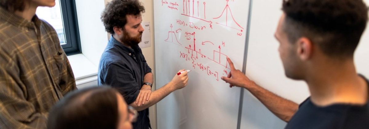 Equipo trabajando frente a una pizarra con ecuaciones