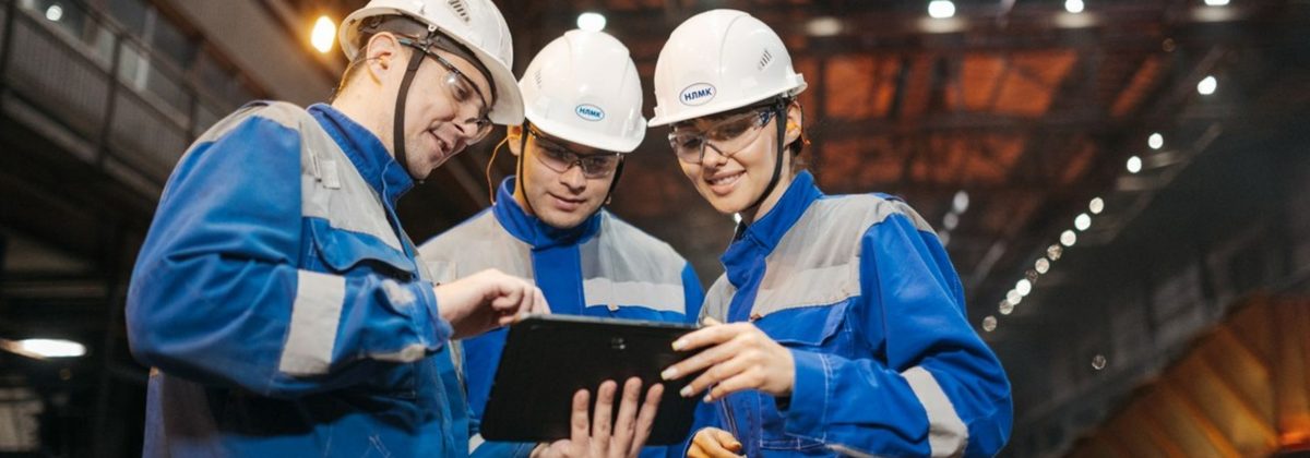 Operarios de fábrica consultando una tableta con equipo de protección